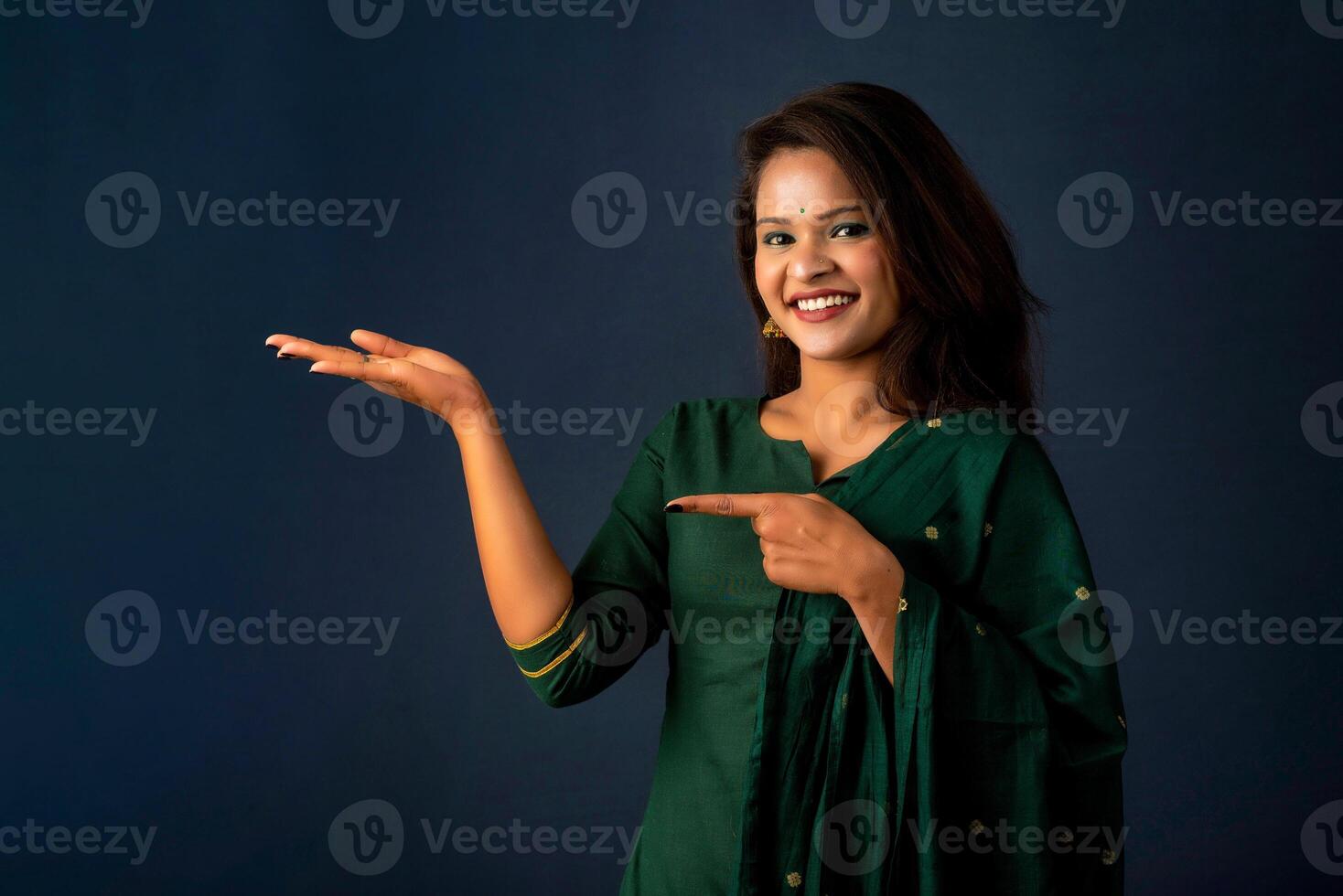 Portrait of a successful cheerful young girl holding and presenting something on hand with a happy smiling face. photo