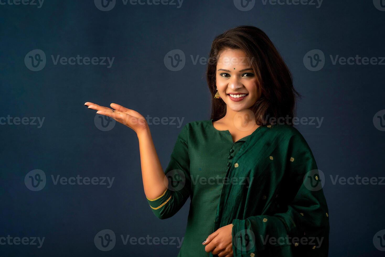 Portrait of a successful cheerful young girl holding and presenting something on hand with a happy smiling face. photo
