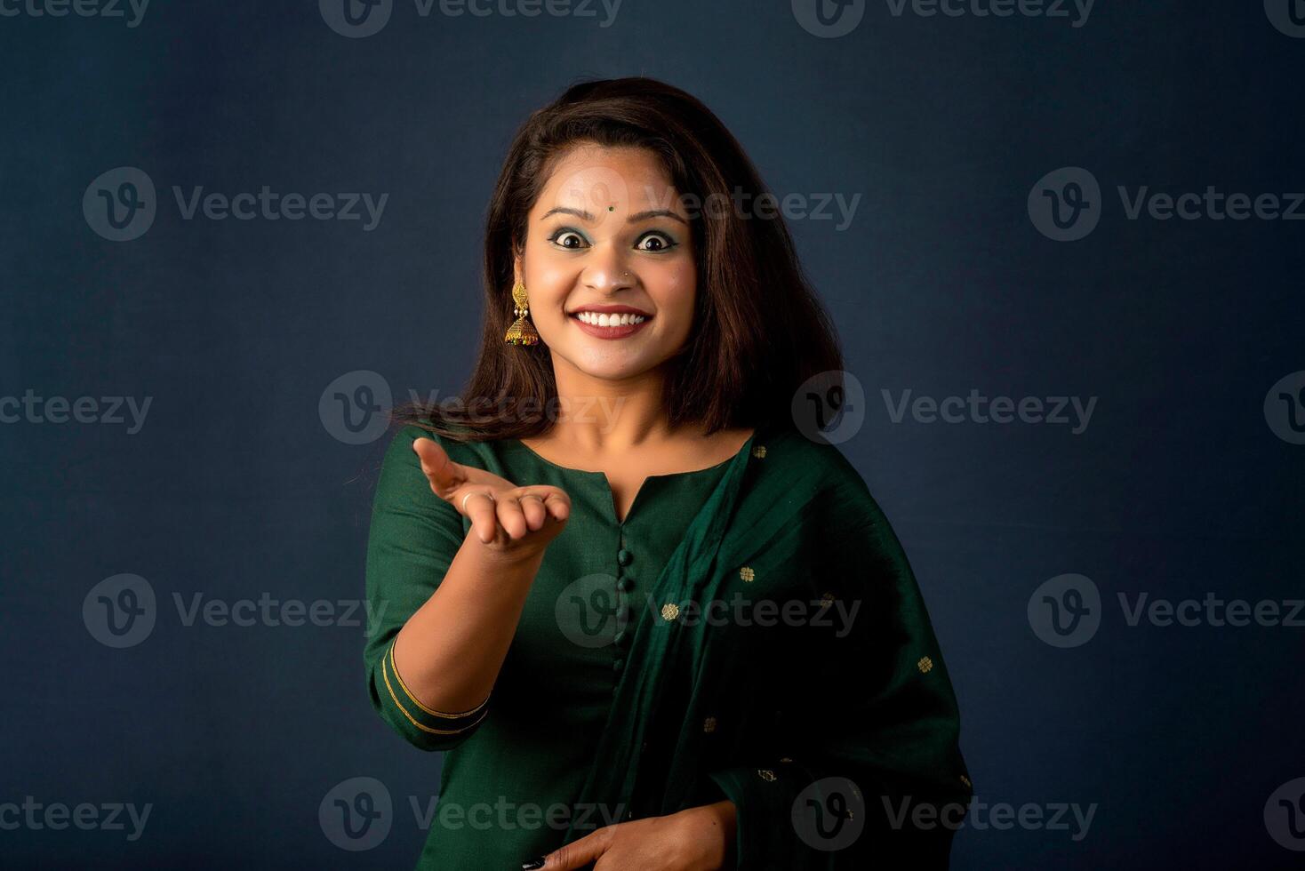 Portrait of a successful cheerful young girl holding and presenting something on hand with a happy smiling face. photo