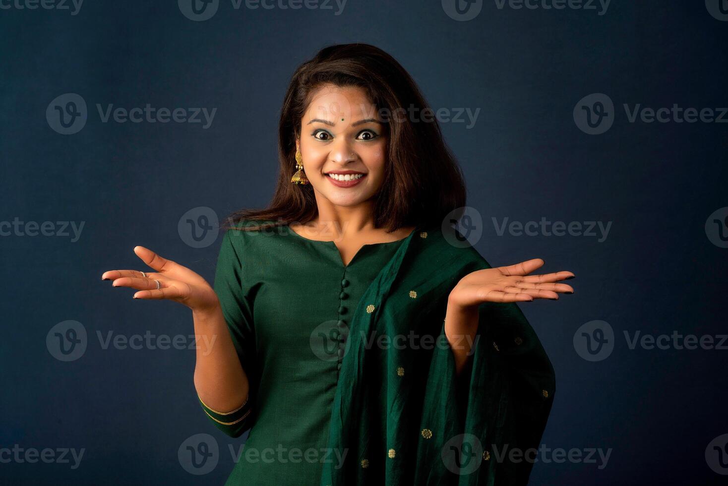 Portrait of a successful cheerful young girl holding and presenting something on hand with a happy smiling face. photo