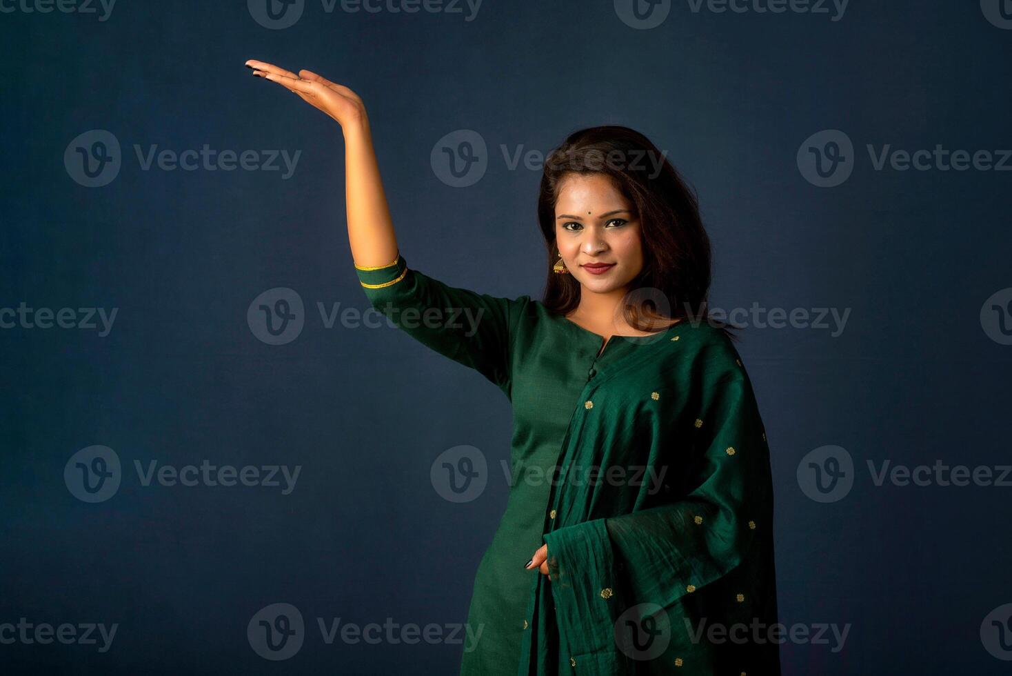 Portrait of a successful cheerful young girl holding and presenting something on hand with a happy smiling face. photo