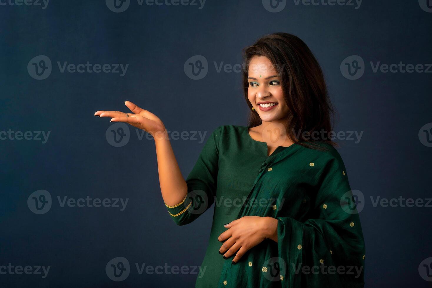 Portrait of a successful cheerful young girl holding and presenting something on hand with a happy smiling face. photo