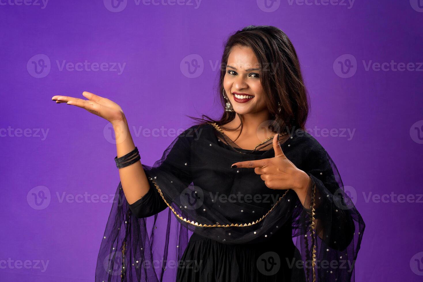 Portrait of a successful cheerful young girl holding and presenting something on hand with a happy smiling face. photo