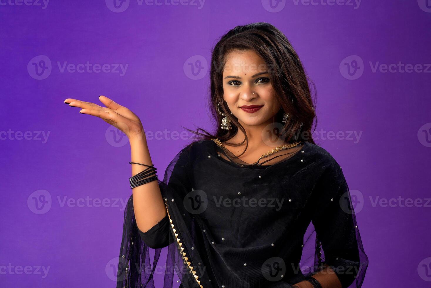 Portrait of a successful cheerful young girl holding and presenting something on hand with a happy smiling face. photo