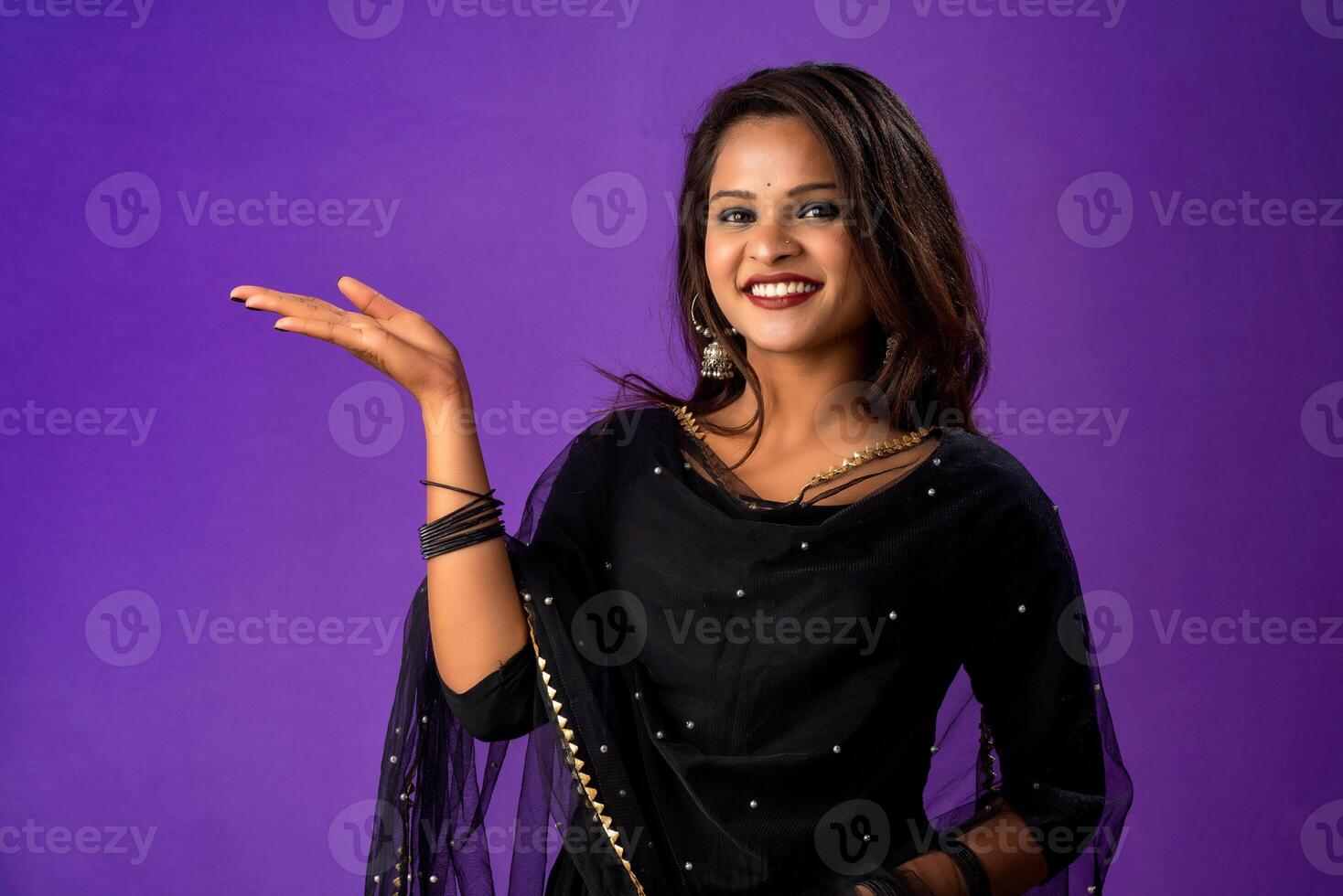 Portrait of a successful cheerful young girl holding and presenting something on hand with a happy smiling face. photo