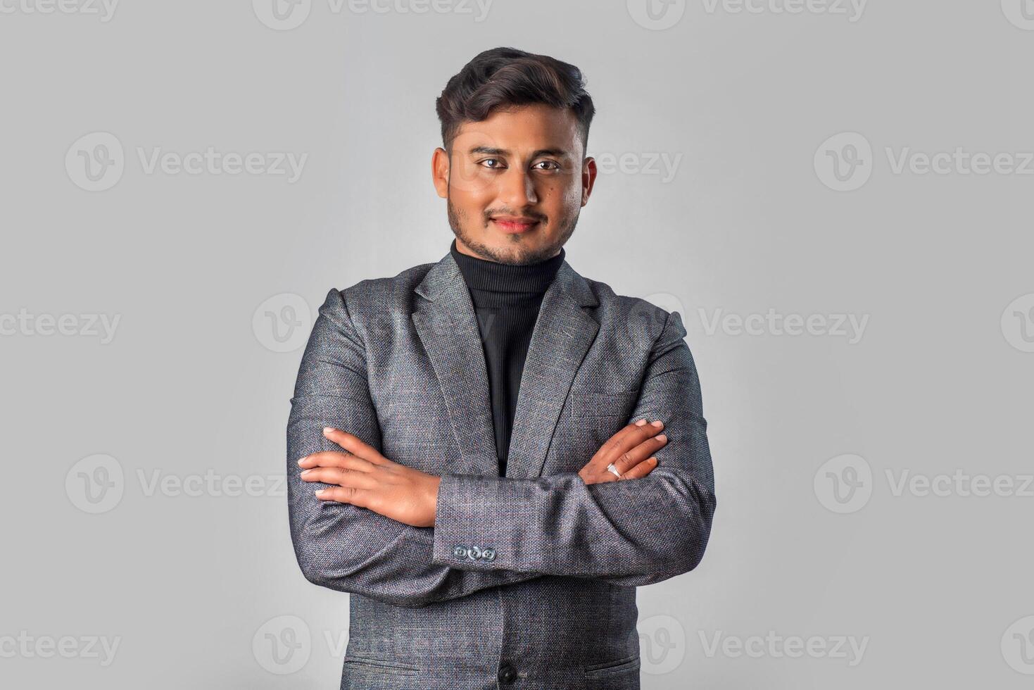 Portrait of Happy Indian young man with arms crossed against a grey background, businessman posing, photo