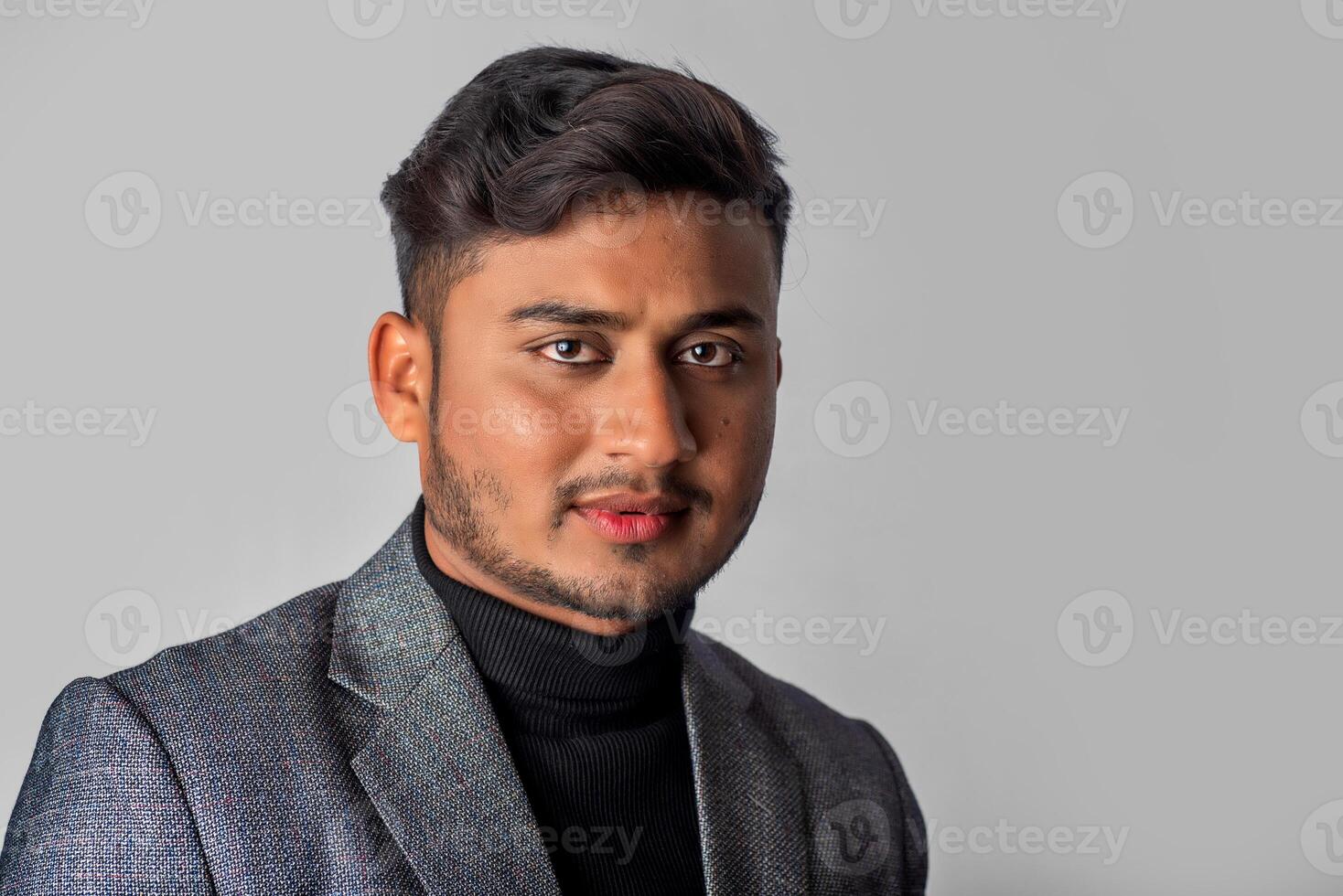 Portrait of Happy Indian young man, businessman wearing a blazer on grey background posing, satisfied successful male in formal suit photo