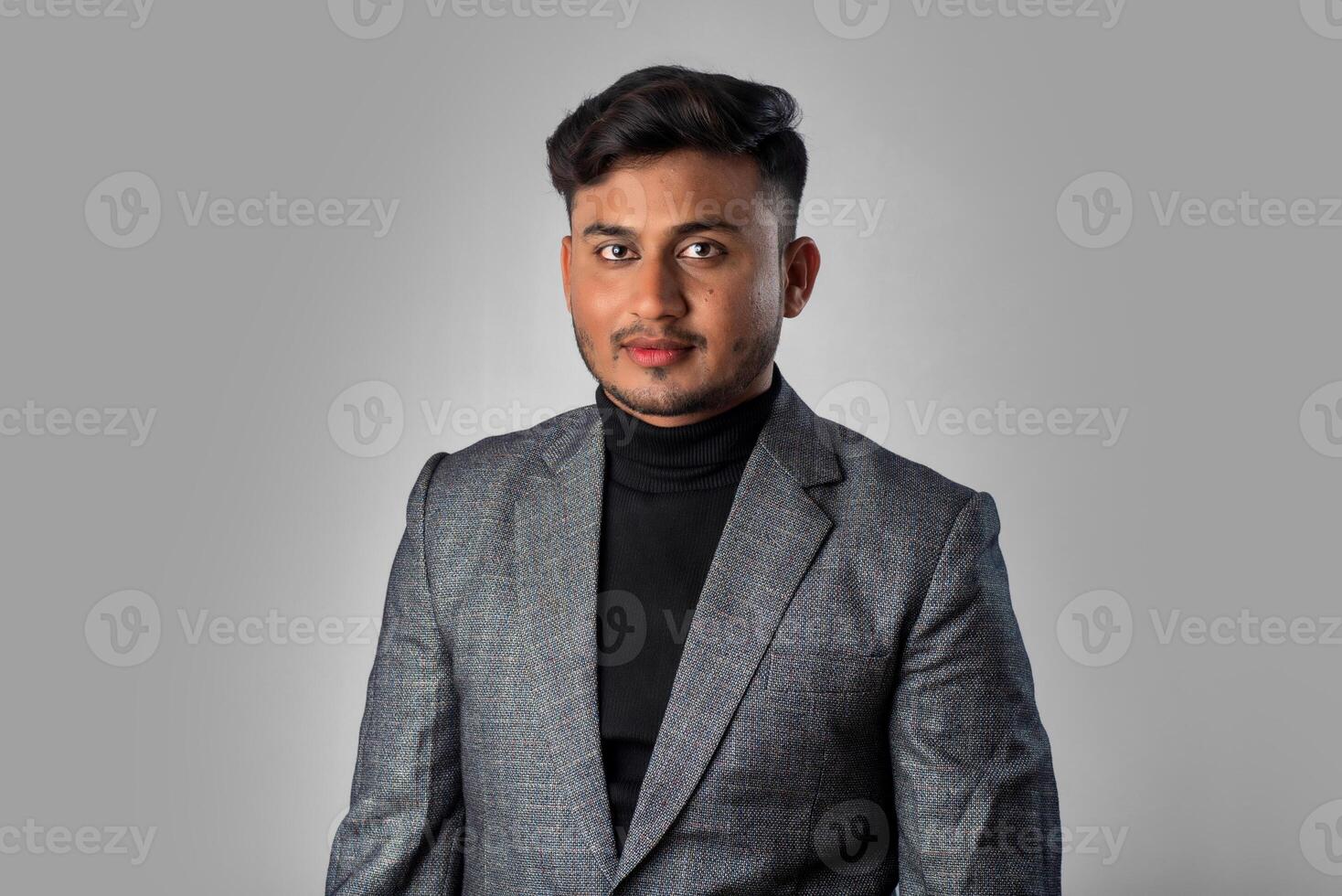 Portrait of Happy Indian young man, businessman wearing a blazer on grey background posing, satisfied successful male in formal suit photo