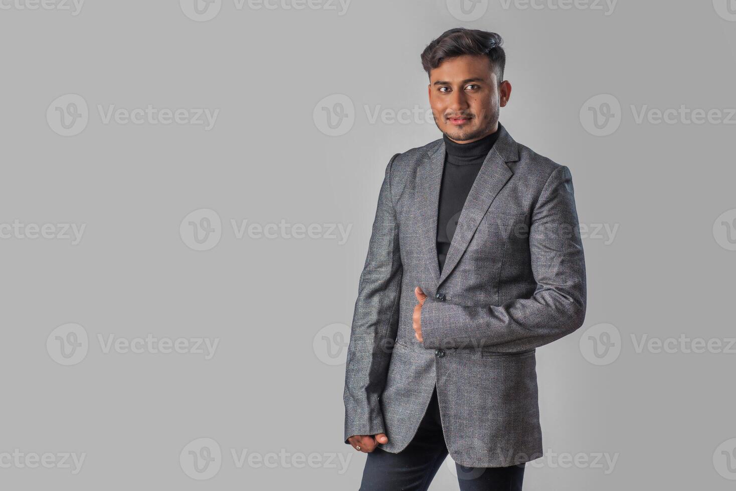 Portrait of Happy Indian young man, businessman wearing a blazer on grey background posing, satisfied successful male in formal suit photo