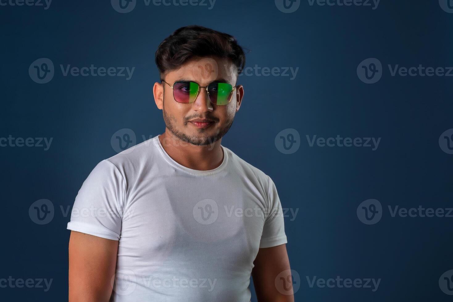 Portrait of Happy Indian young man with eyeglasses posing on a blue background photo