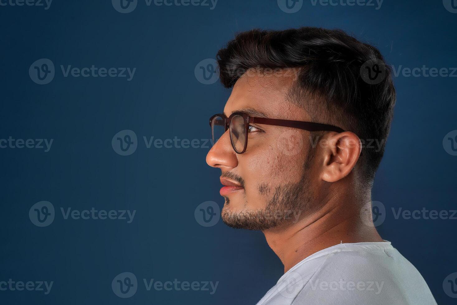 Portrait of Happy Indian young man with eyeglasses posing on a blue background photo