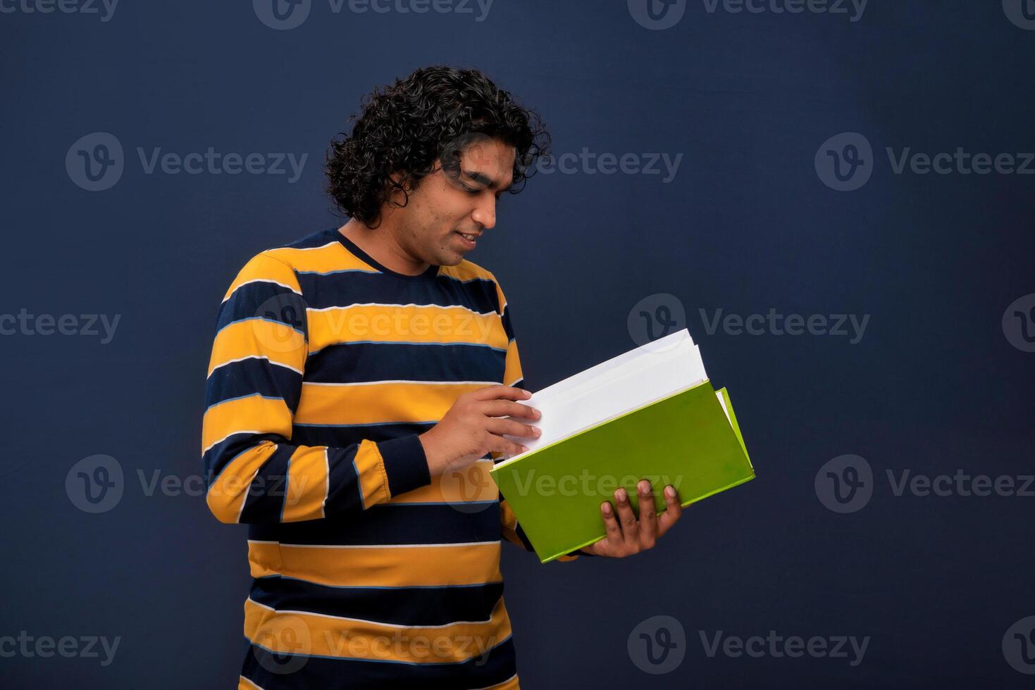 Young happy man holding and posing with the book on gray background. photo