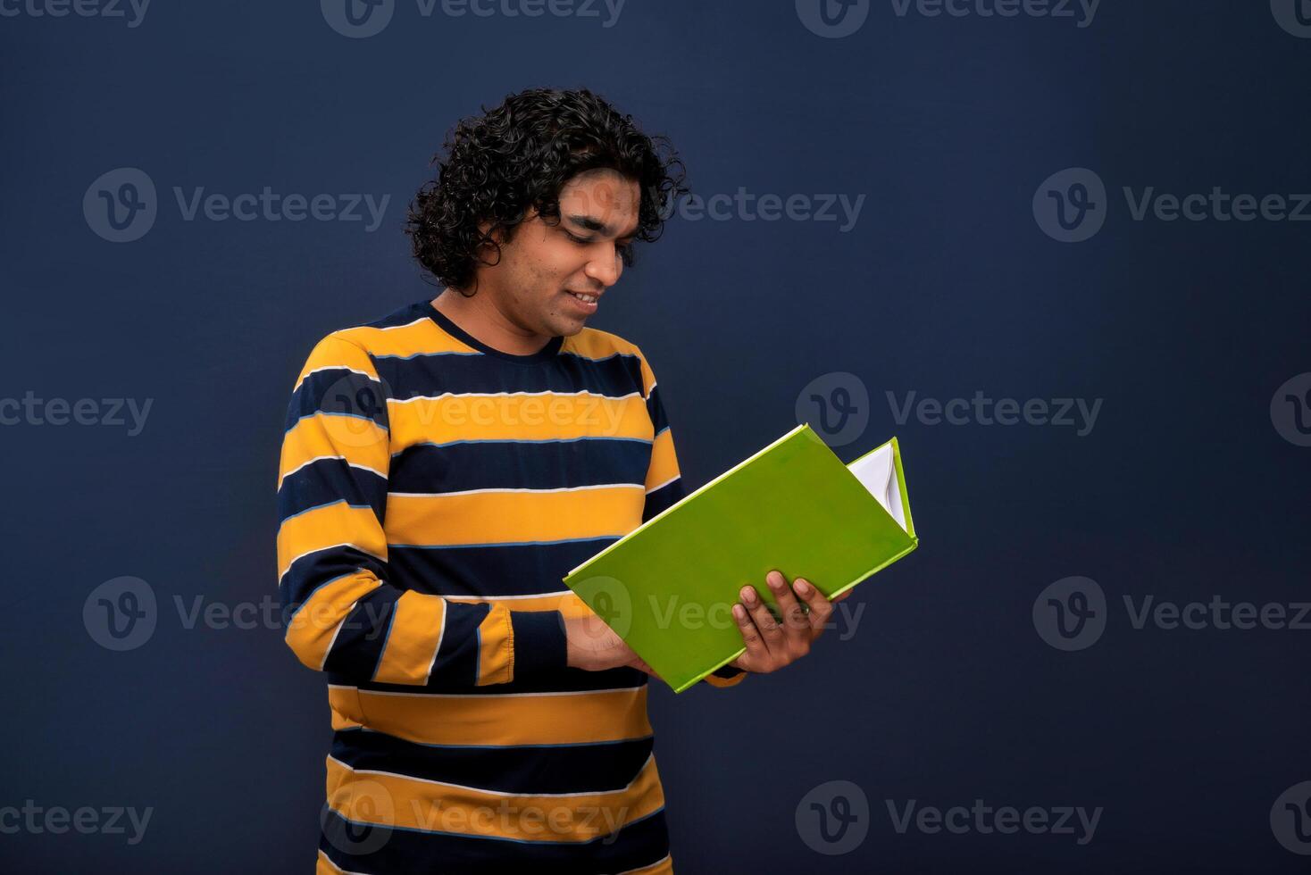 Young happy man holding and posing with the book on gray background. photo