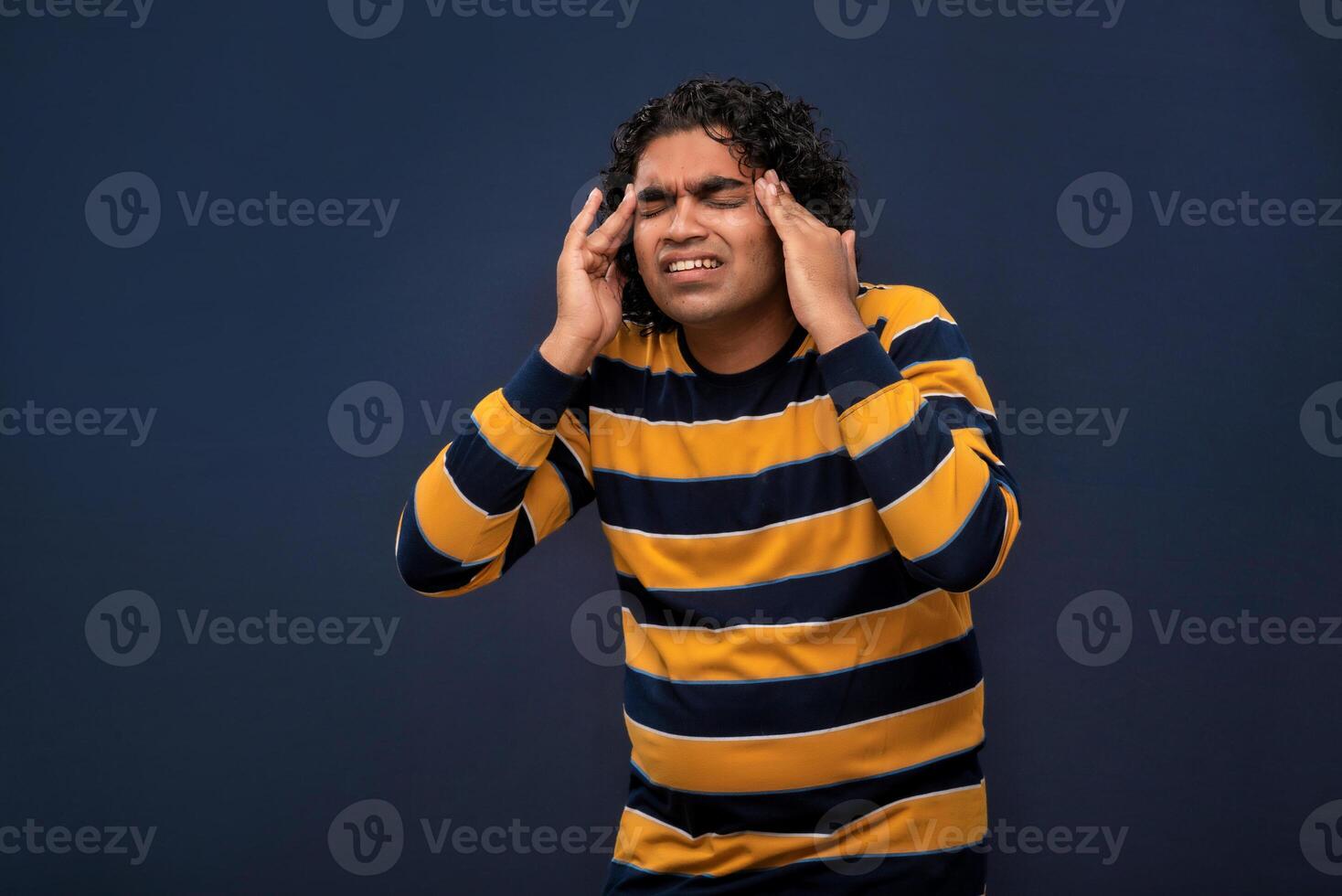 Portrait of young man stress or having the pain of a headache on a grey background. photo