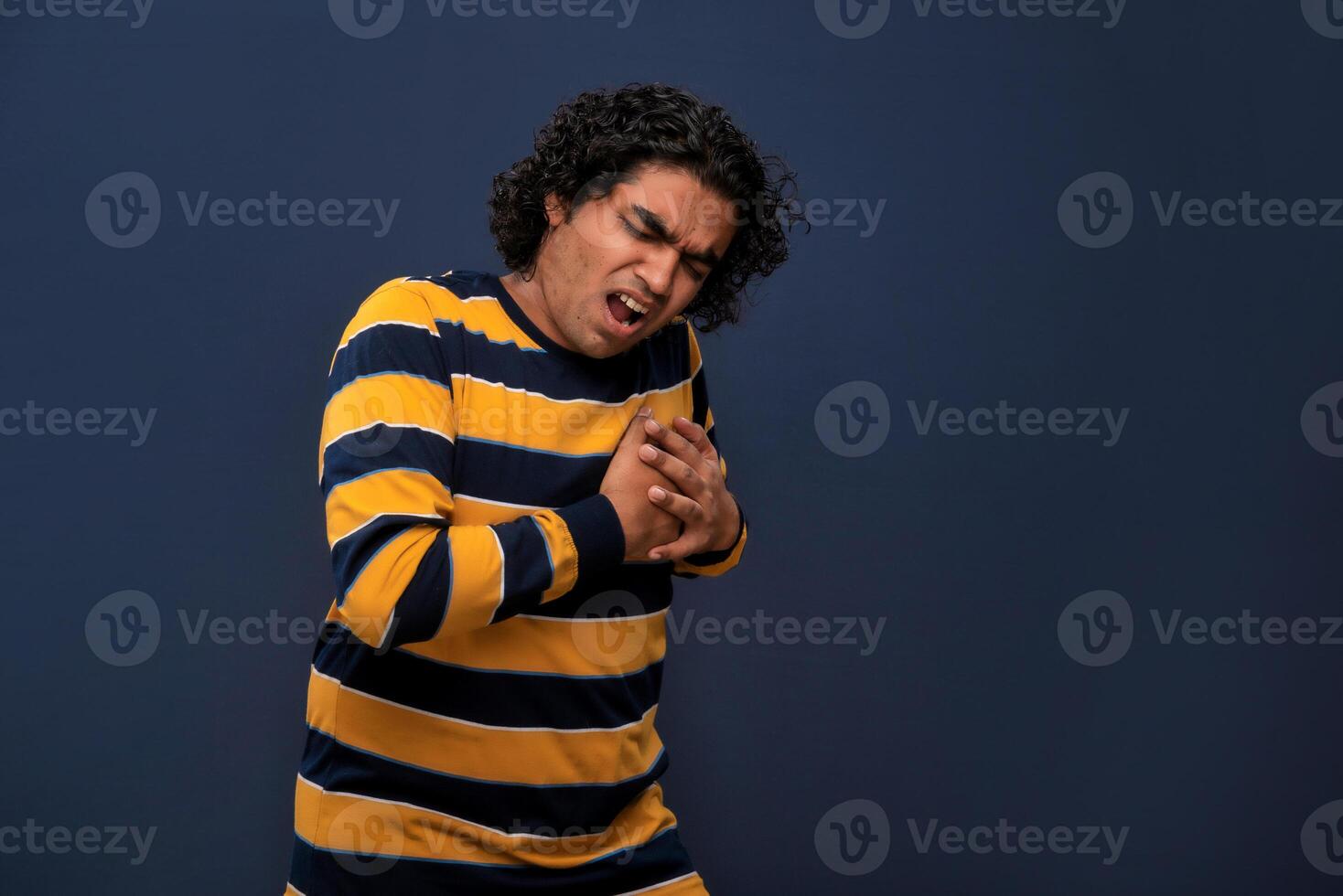 A man in a striped shirt is holding his chest photo