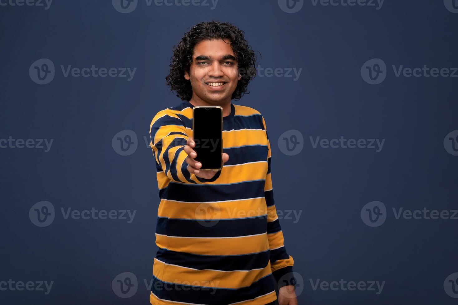 Young handsome young man, businessman showing a blank screen of smartphone or mobile or tablet phone on grey background photo