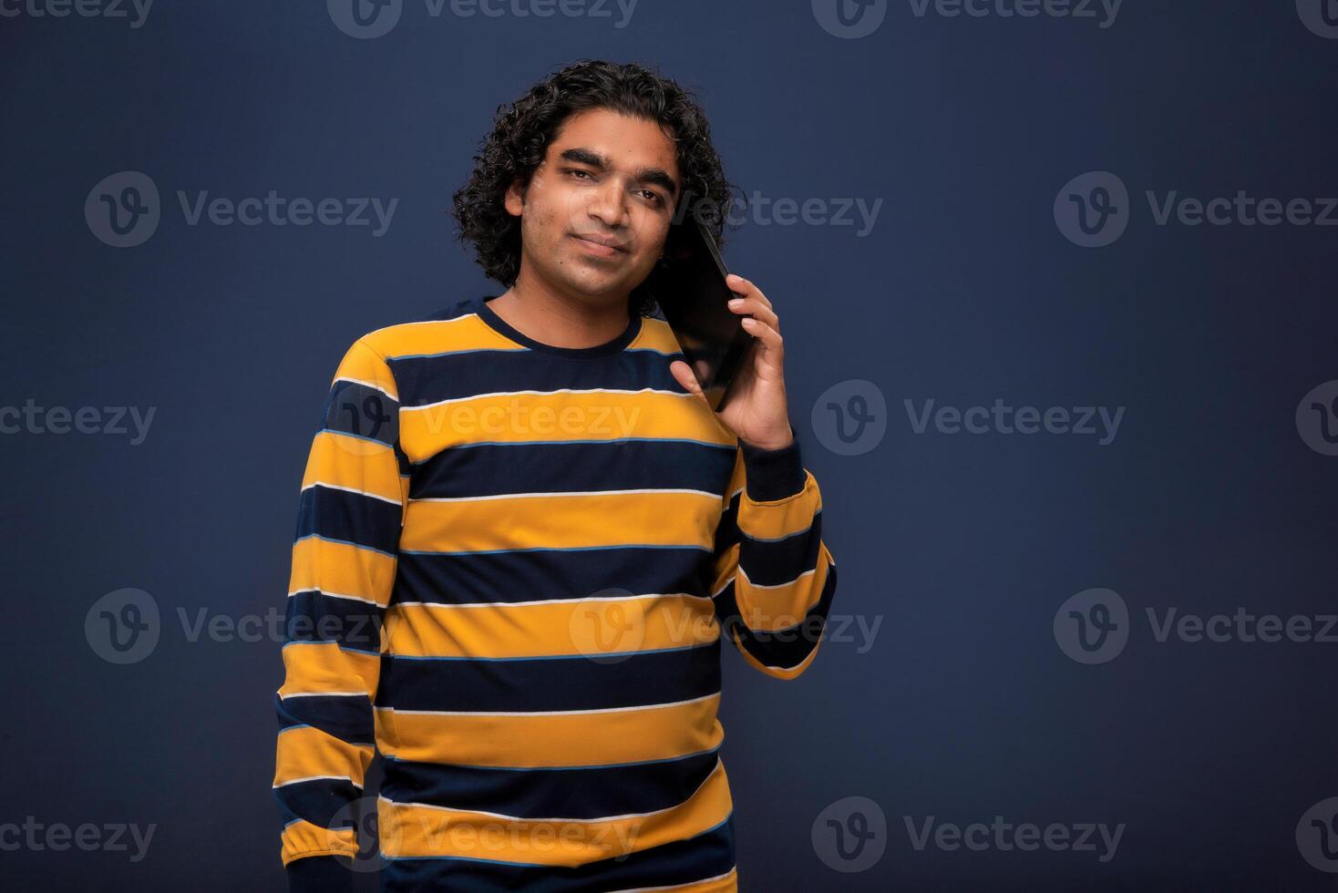 Young handsome young man holding and using smartphone or mobile or tablet phone on grey background photo