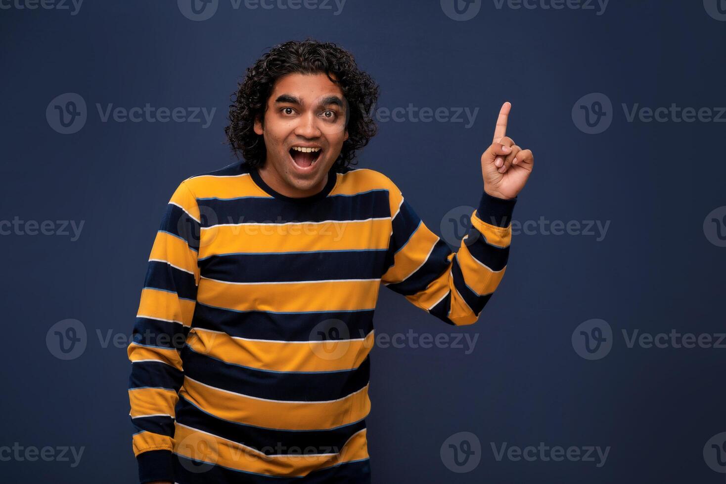 Portrait of a successful cheerful young man pointing and presenting something with hand or finger with a happy smiling face. photo