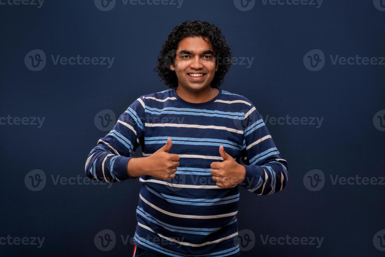 Portrait of a successful cheerful young man pointing and presenting ok, victory sign with hand or finger with a happy smiling face. photo