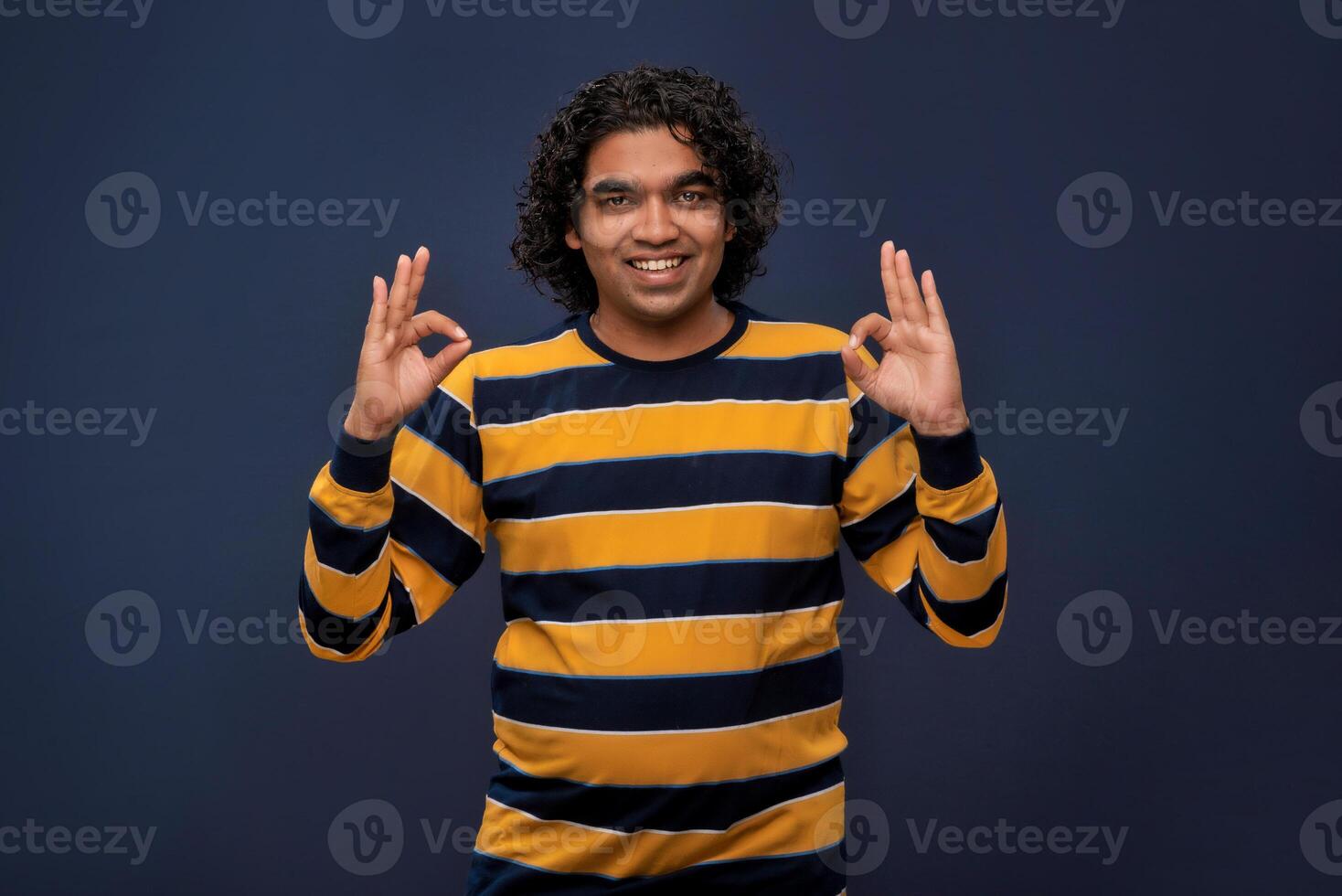 Portrait of a successful cheerful young man pointing and presenting ok, victory sign with hand or finger with a happy smiling face. photo
