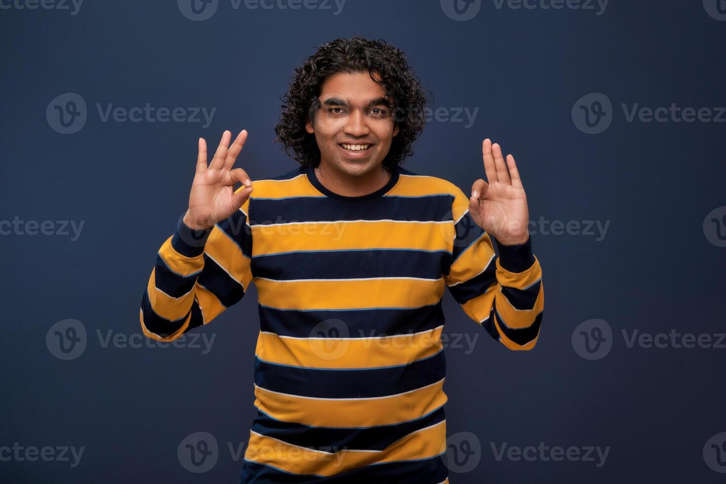 Portrait of a successful cheerful young man pointing and presenting ok, victory sign with hand or finger with a happy smiling face. photo