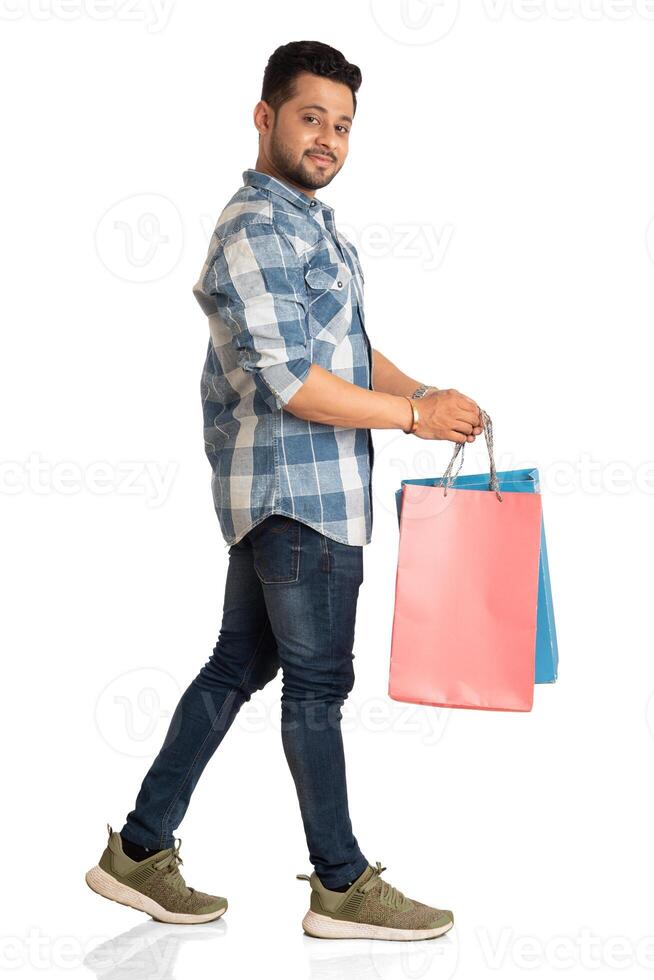 Young handsome man holding and posing with shopping bags on a white background photo