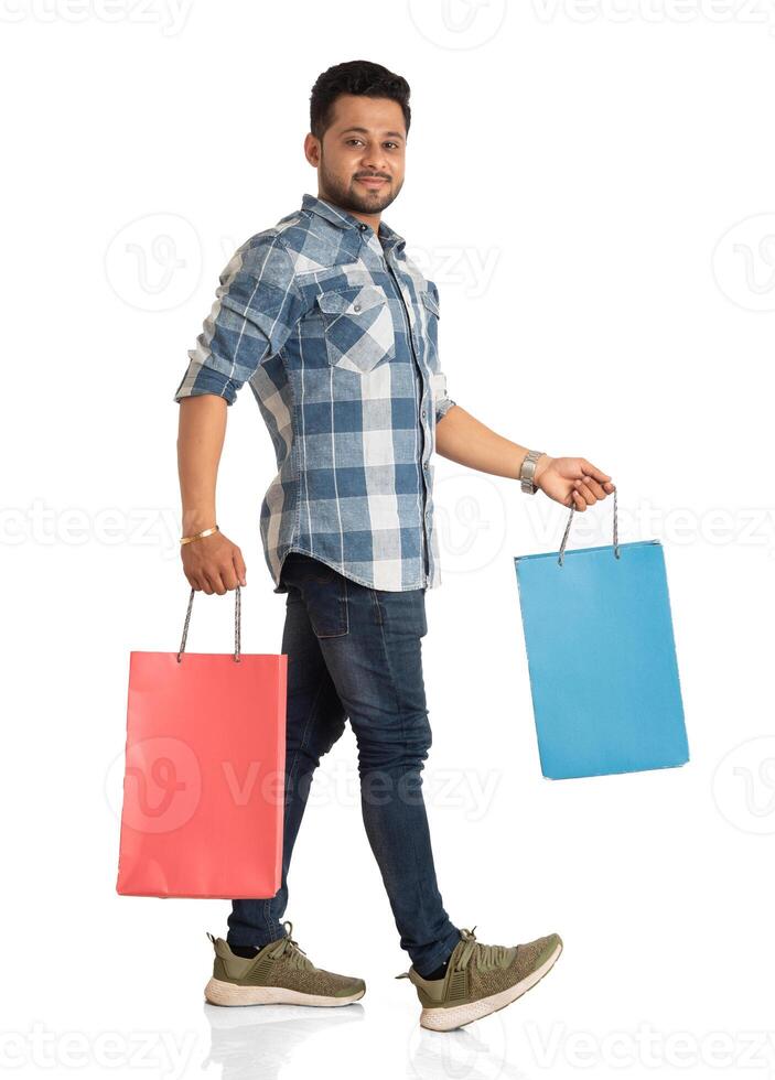 Young handsome man holding and posing with shopping bags on a white background photo