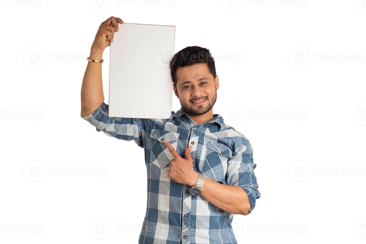 A happy young man holding and displaying a signboard or placard in his hands on a white background. photo