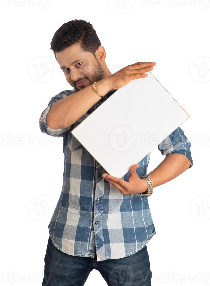 A happy young man holding and displaying a signboard or placard in his hands on a white background. photo