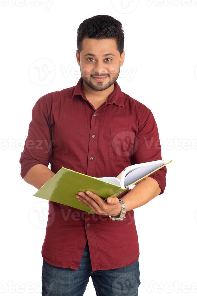 Young happy man holding and posing with the book on white background. photo