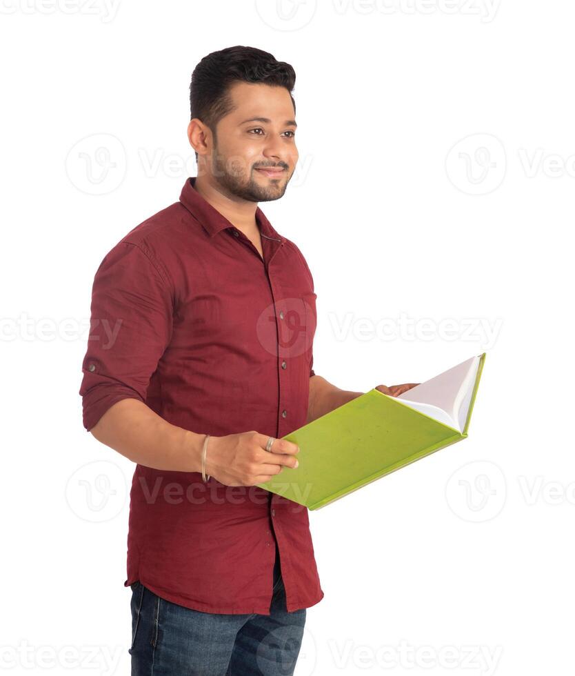Young happy man holding and posing with the book on white background. photo