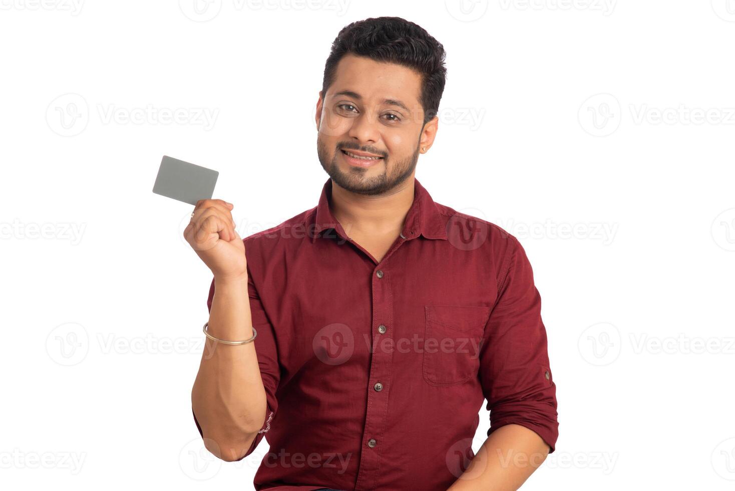 Young smiling handsome man posing with a credit or debit card on white background. photo
