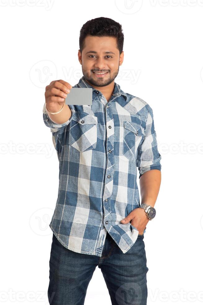 Young smiling handsome man posing with a credit or debit card on white background. photo