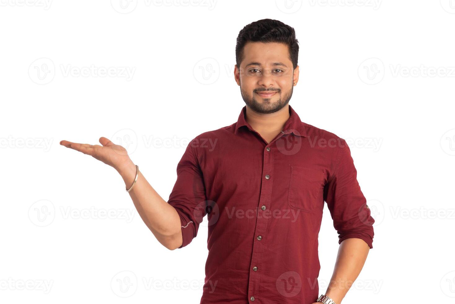 Portrait of a successful cheerful young man holding and presenting something on hand with a happy smiling face. photo