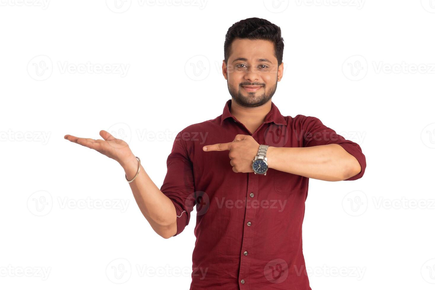 Portrait of a successful cheerful young man holding and presenting something on hand with a happy smiling face. photo