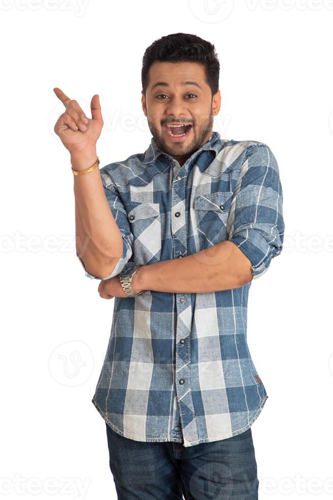 Portrait of a successful cheerful young man pointing and presenting something with hand or finger with a happy smiling face. photo