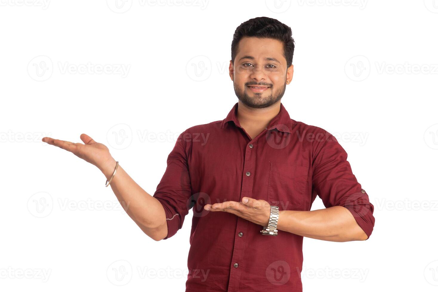 Portrait of a successful cheerful young man holding and presenting something on hand with a happy smiling face. photo