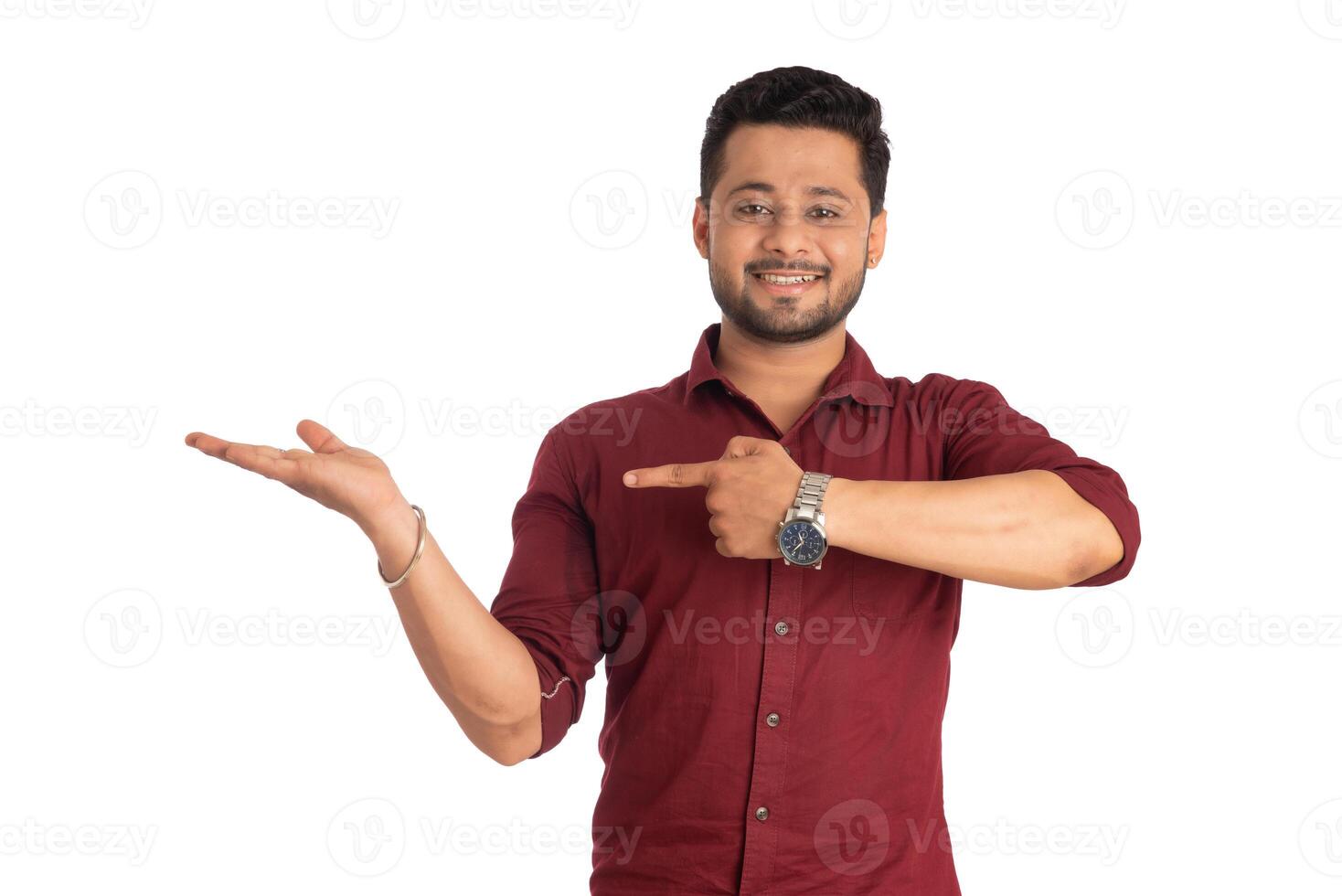 Portrait of a successful cheerful young man holding and presenting something on hand with a happy smiling face. photo