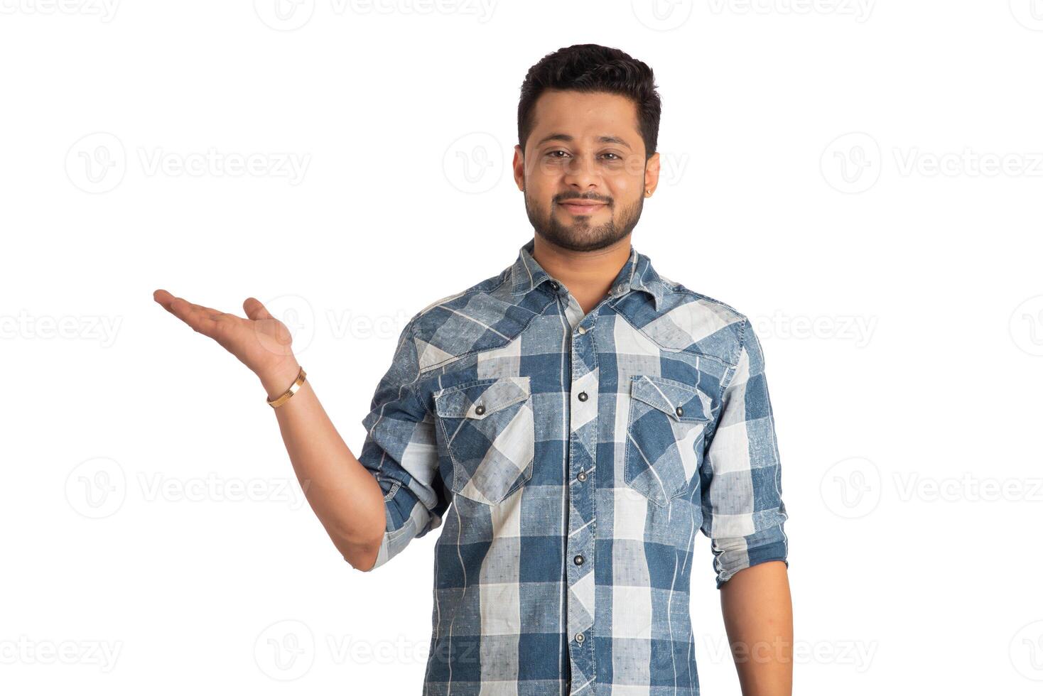 Portrait of a successful cheerful young man holding and presenting something on hand with a happy smiling face. photo