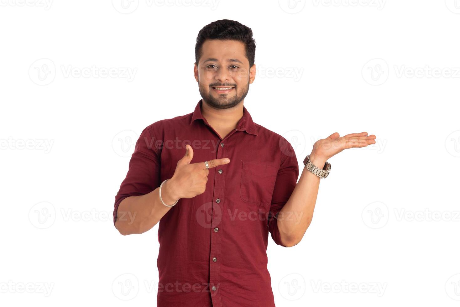 Portrait of a successful cheerful young man holding and presenting something on hand with a happy smiling face. photo