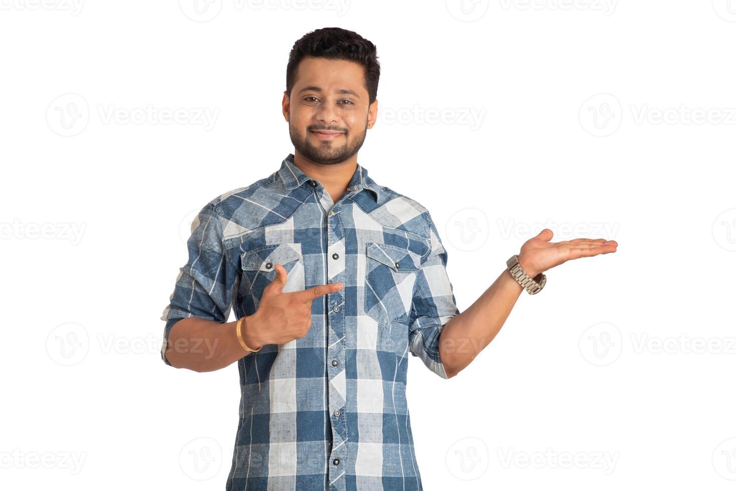 Portrait of a successful cheerful young man holding and presenting something on hand with a happy smiling face. photo