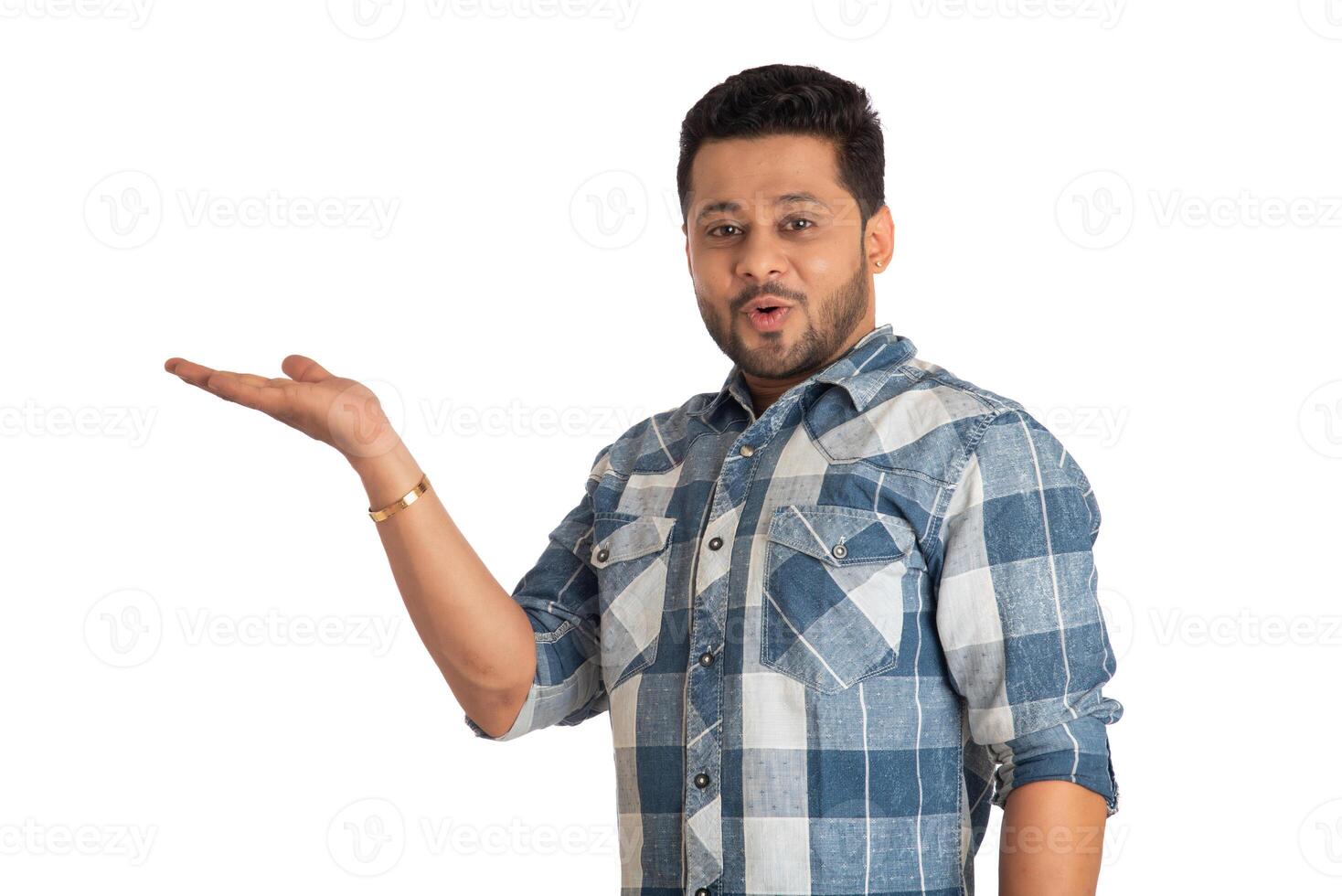 Portrait of a successful cheerful young man holding and presenting something on hand with a happy smiling face. photo