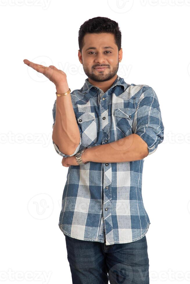 Portrait of a successful cheerful young man holding and presenting something on hand with a happy smiling face. photo