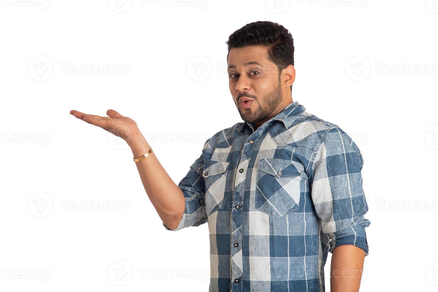 Portrait of a successful cheerful young man holding and presenting something on hand with a happy smiling face. photo