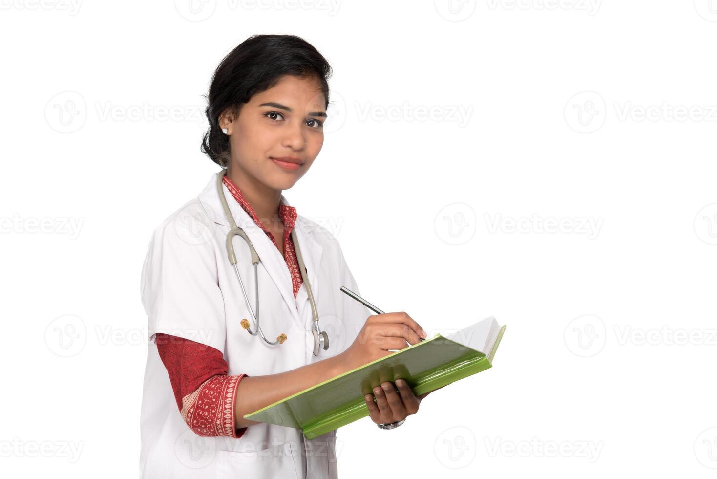 Young woman doctor with stethoscope is writing in book photo