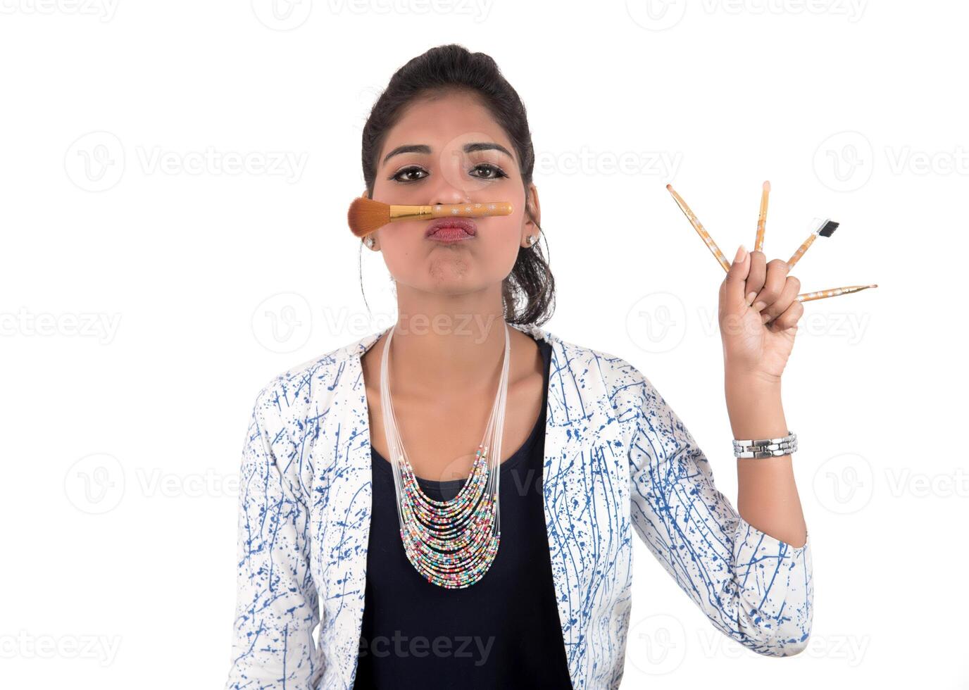 Beautiful young girl enjoying with makeup brushes isolated on white photo