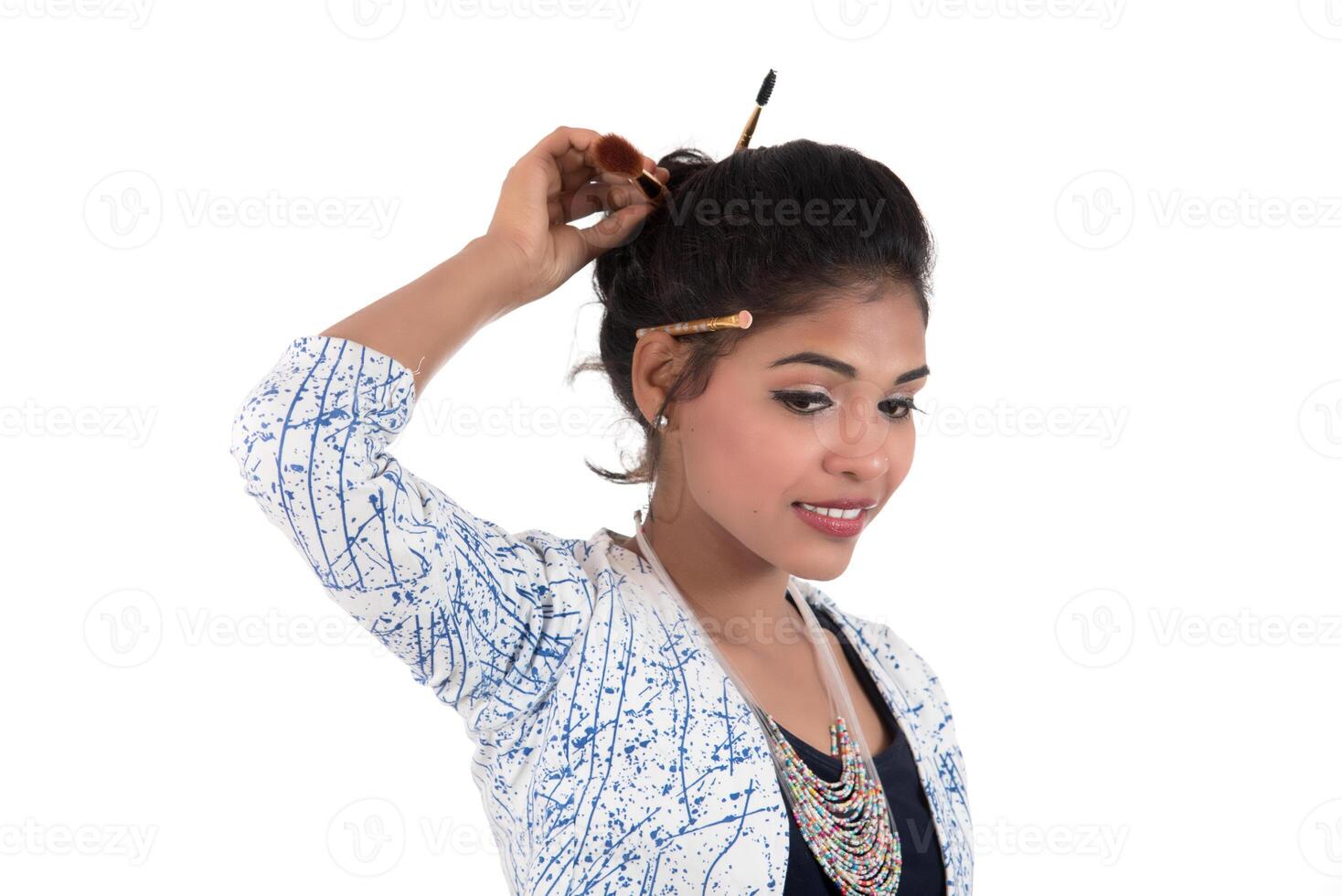 Beautiful young girl enjoying with makeup brushes isolated on white photo