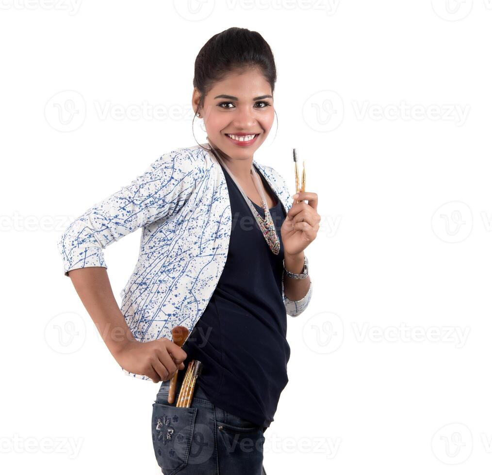 Beautiful young girl enjoying with makeup brushes isolated on white photo