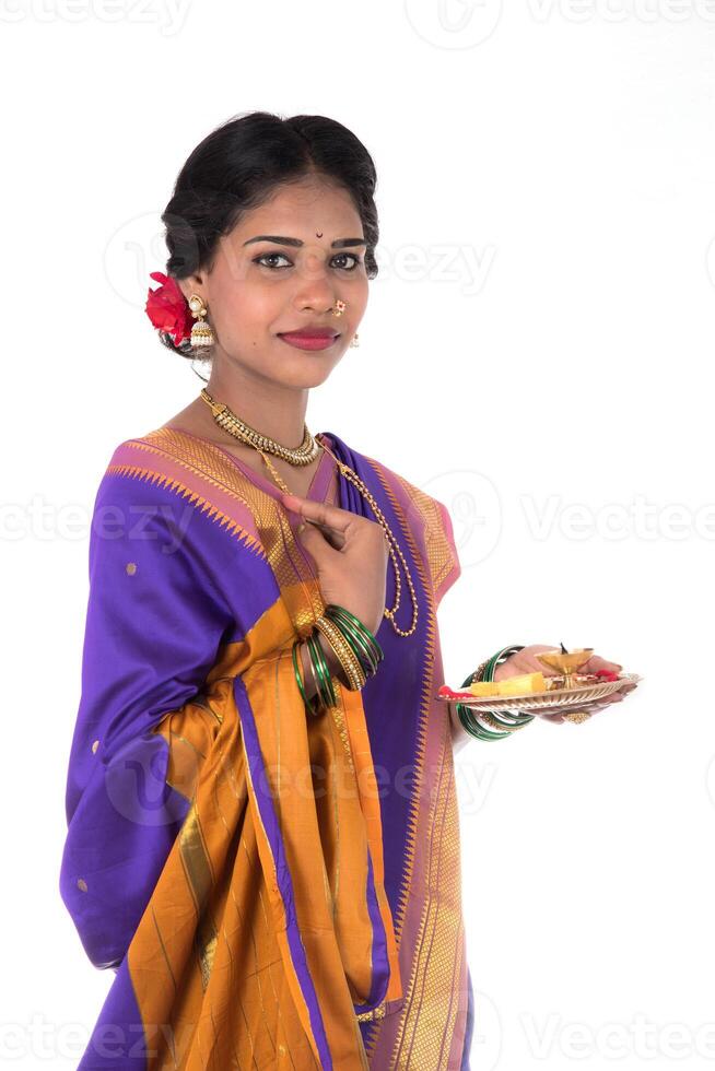 Indian woman performing worship, portrait of a beautiful young lady with pooja thali isolated on white background photo