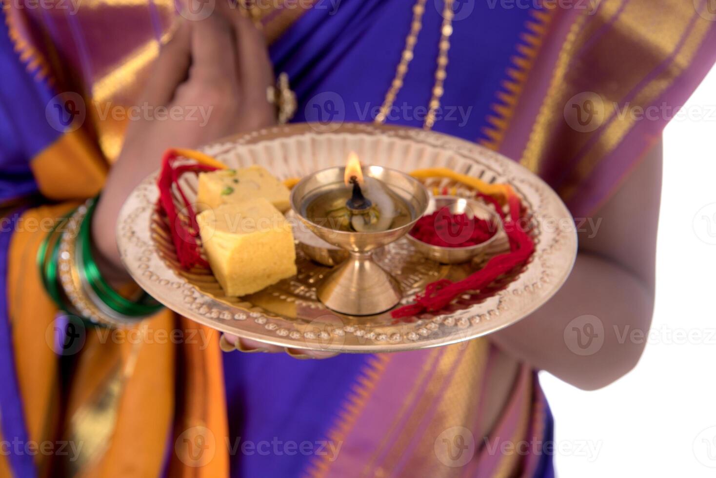 Indian woman performing worship, portrait of a beautiful young lady with pooja thali isolated on white background photo